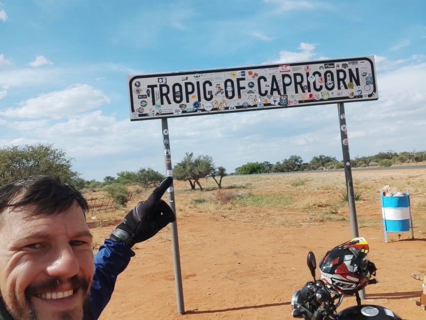 Alex Tibola smiling at the Tropic of Capricorn sign with his Nippon 150